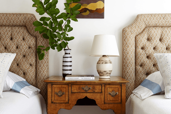 一间带簇绒床头板和古董床头柜的卧室