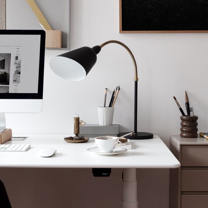 与宜家办公桌和黑色任务灯黑与白的斯堪的纳维亚的家庭办公区域。