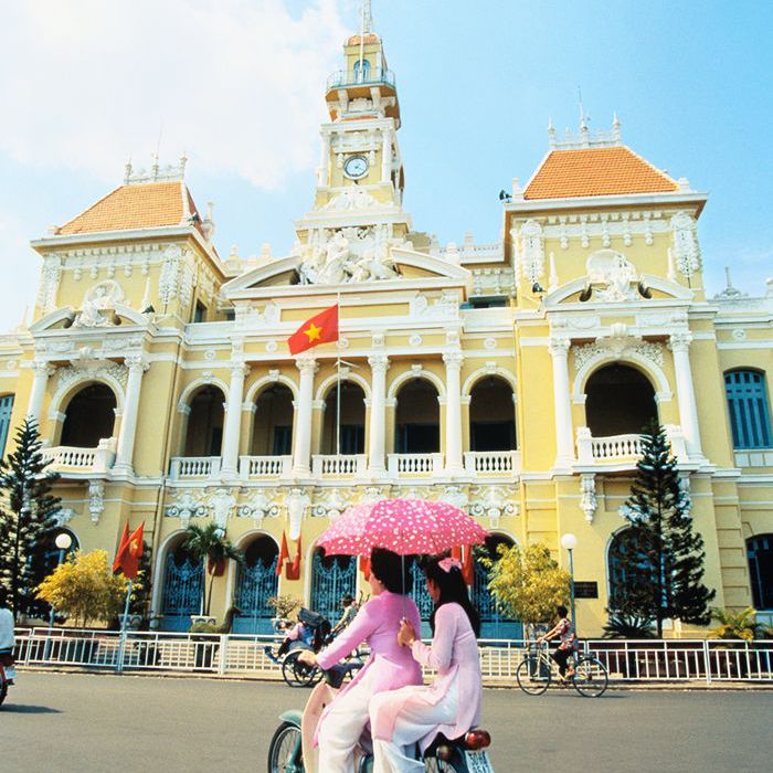 两个女人骑摩托车在越南的胡志明市街头。