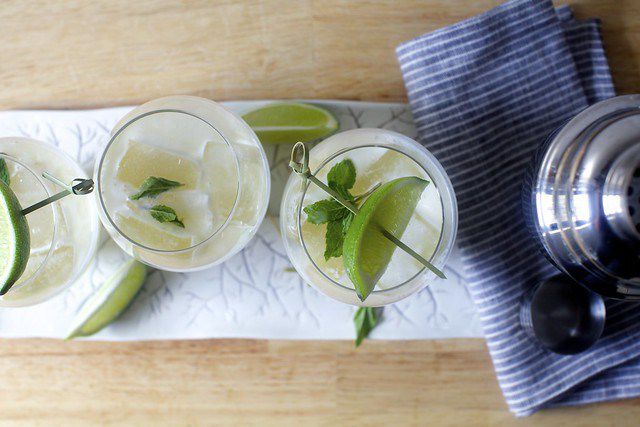 在盘子的三个鸡尾酒，坐在鸡尾酒瓶旁边。