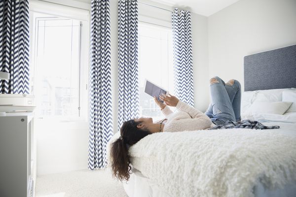 Young woman using digital tablet on bed