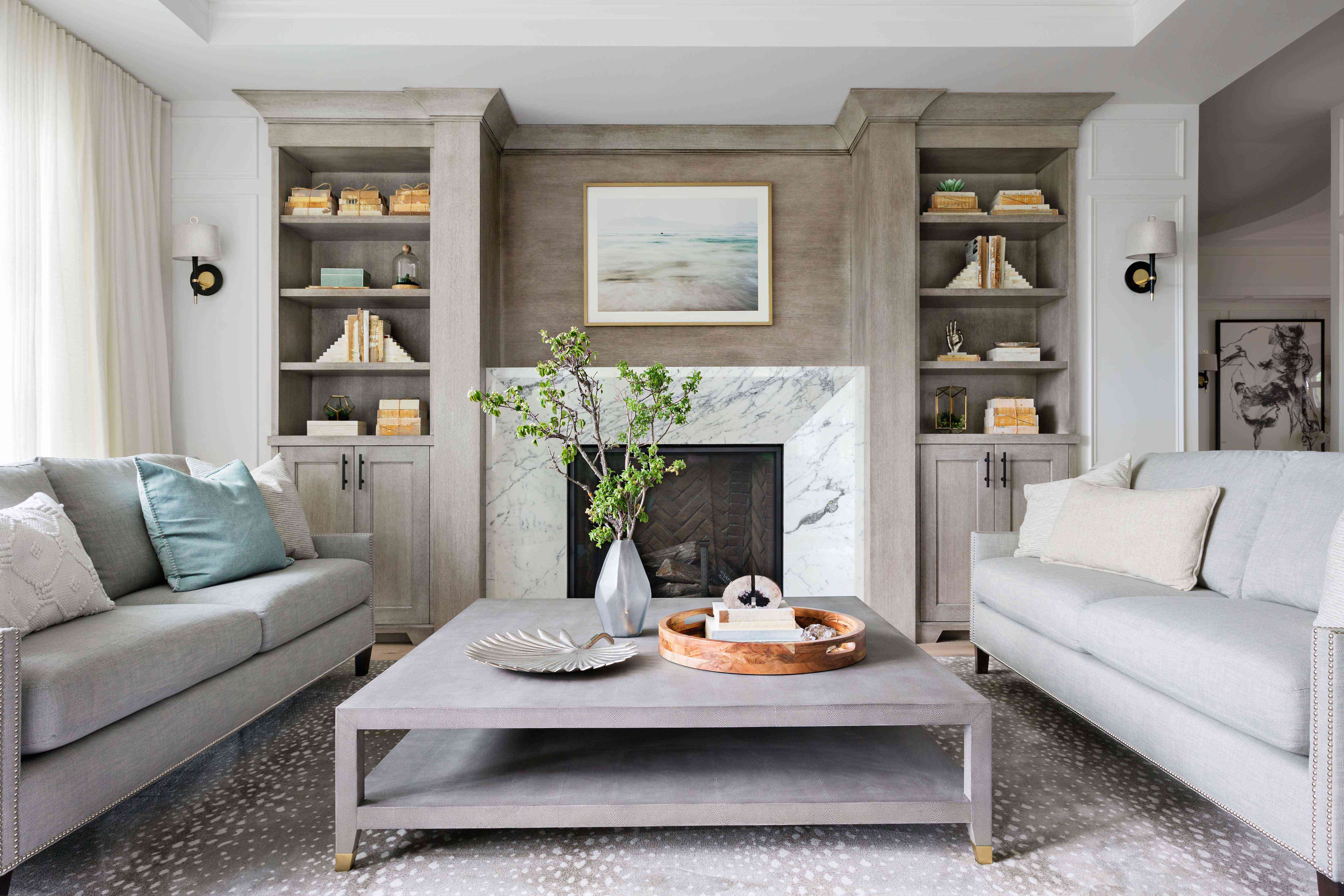 带有白色大理石壁炉的起居室，由定制搁架侧翼