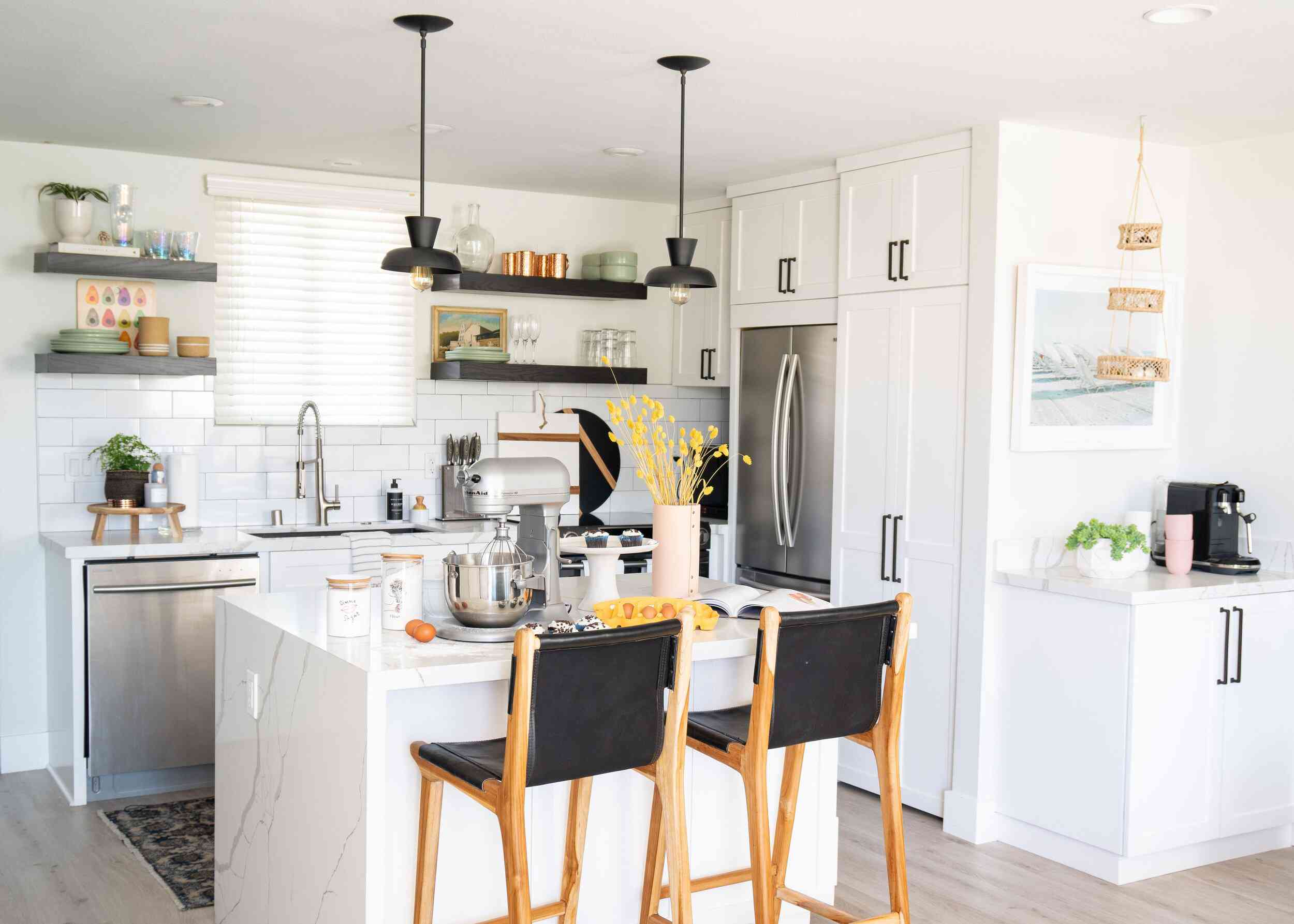 一个带有颜色协调厨具和几个装饰黑色口音的小型白色厨房