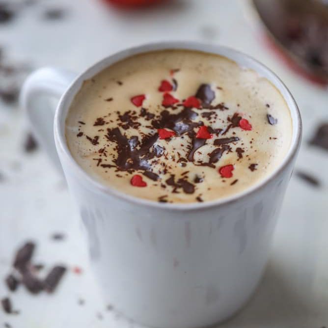 一个白色的咖啡杯，上面有一层红色的心型糖屑。