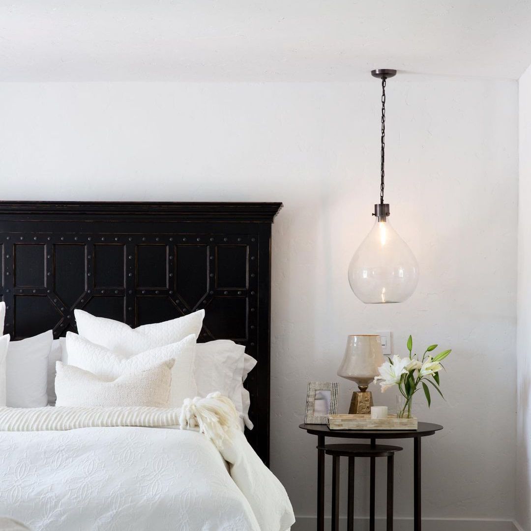 卧室配有大的黑色床架和玻璃吊灯。
