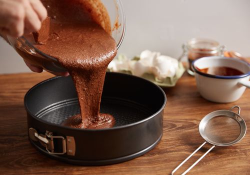 chocolate cake batter being poured into a pan