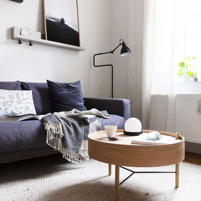 客厅有圆咖啡桌，编织地毯和深蓝色沙发”class=