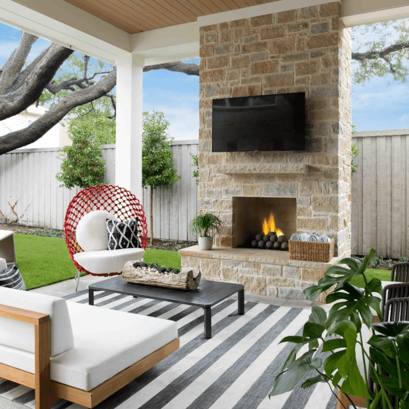 覆盖的庭院装饰有户外壁炉，大型电视，条纹地毯和充足的舒适座位