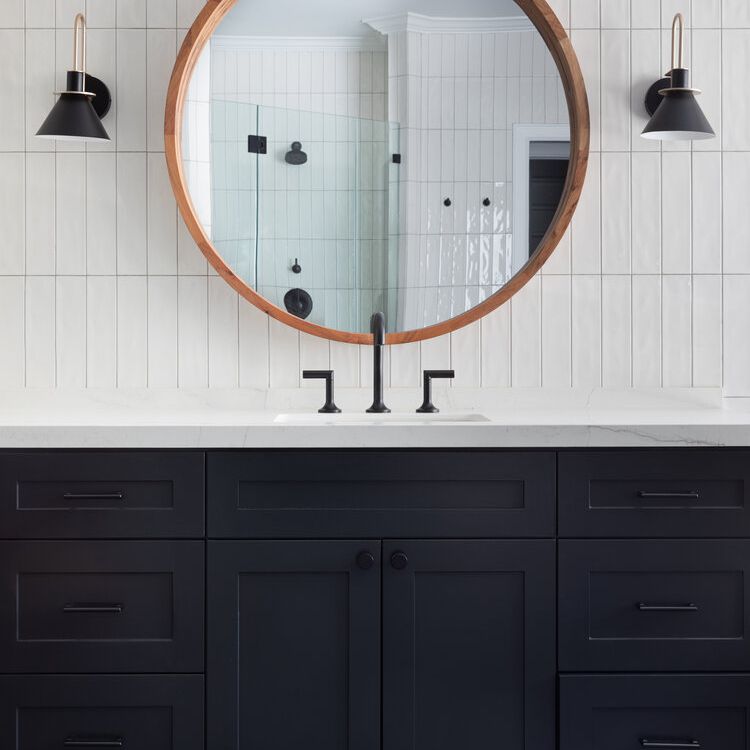 浴室里有海军蓝的橱柜和贴着白色瓷砖的后挡板