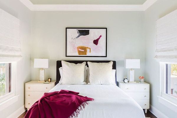 中央的床与枝形吊灯和紫红色的扔在床的角落覆盖