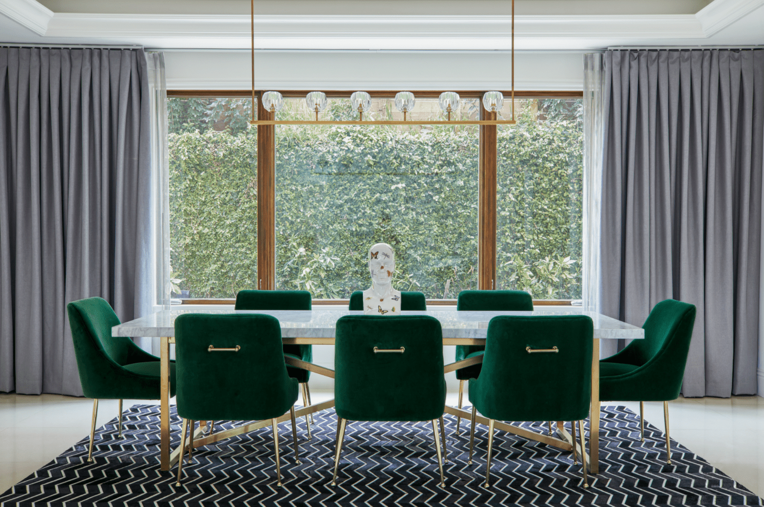 一间餐厅，有一扇大窗户，两侧挂着厚厚的灰色窗帘，从窗户一直挂到墙壁