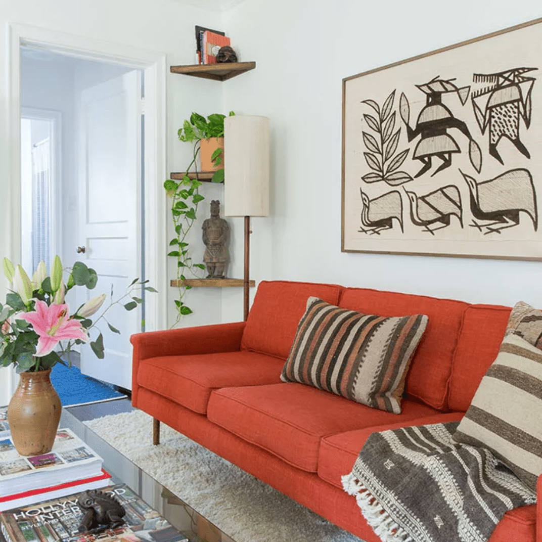 客厅里有焦橙色的沙发，咖啡桌上有镶框的艺术品和植物