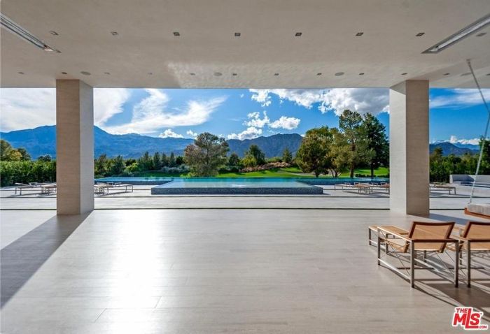 悬挑和石头地板通向一个无边泳池，可以看到远处的山脉。