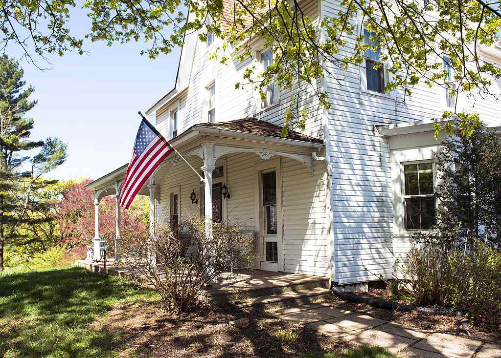什么是农舍？有130年历史的白色农舍，有墙板、前廊和一面美国国旗
