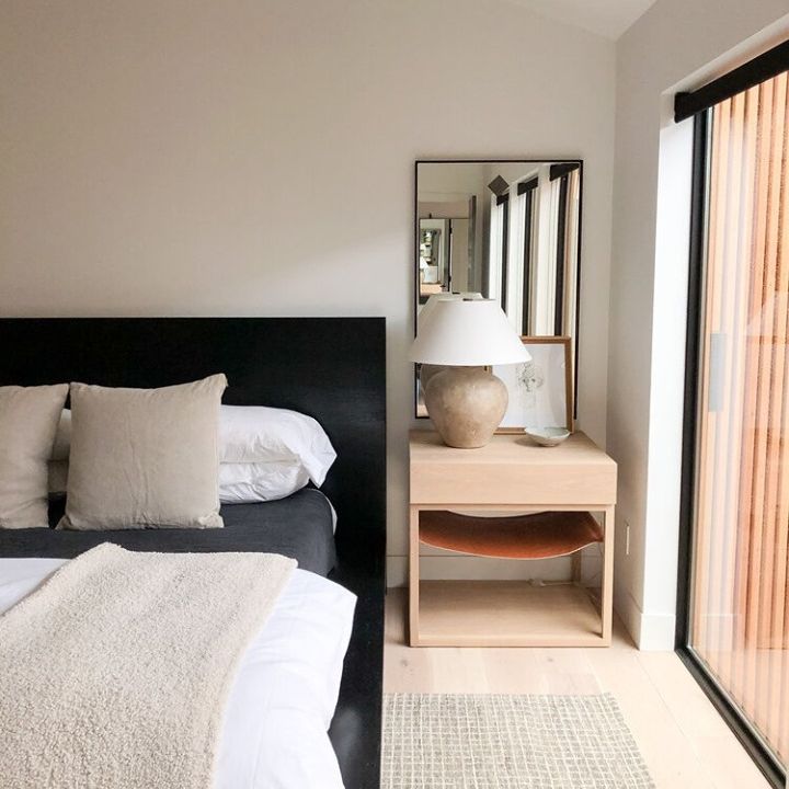 中性卧室，黑色床头板和浅色木质边桌。