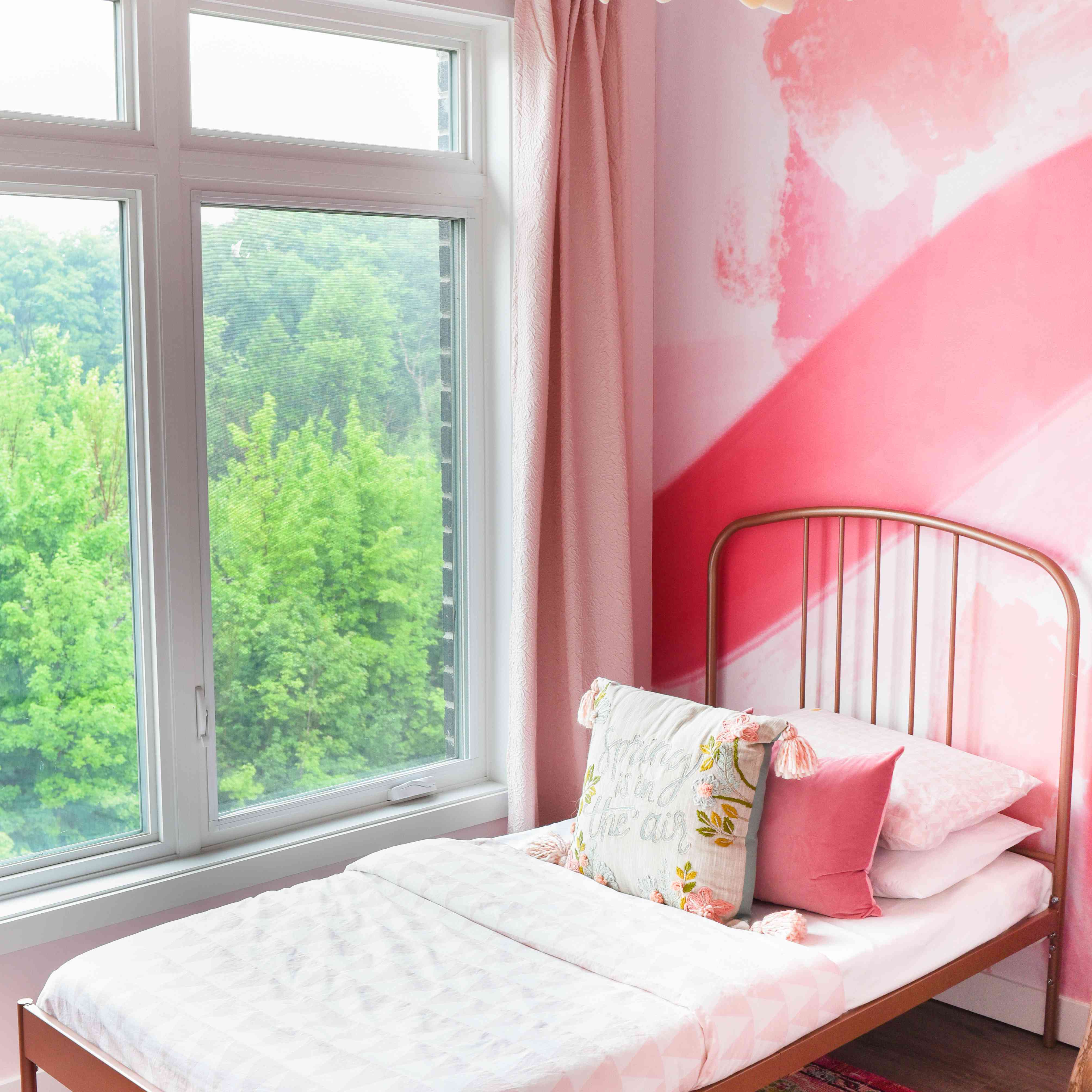 之后的照片，粉红色的卧室与金属双人床框架。“class=