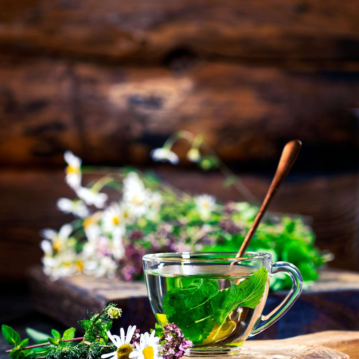 新鲜香草和鲜花在透明的玻璃茶杯上木砧板