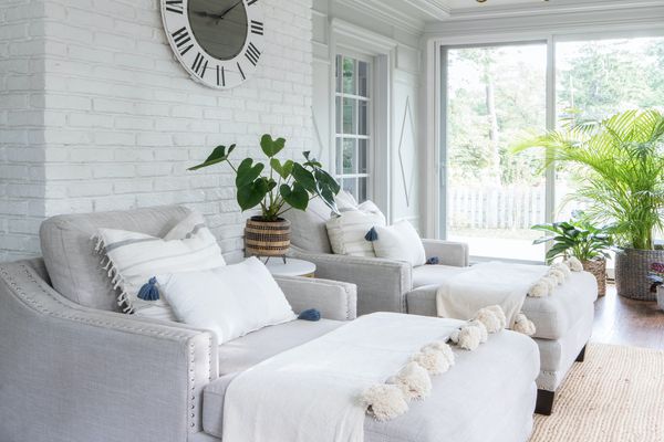 与白色砖墙，灰色躺椅和植物的日光浴室。