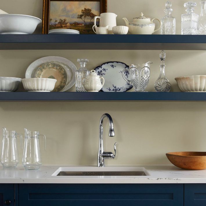 深蓝色开放的架子展示古董盘子，水晶滗水器，和一幅画