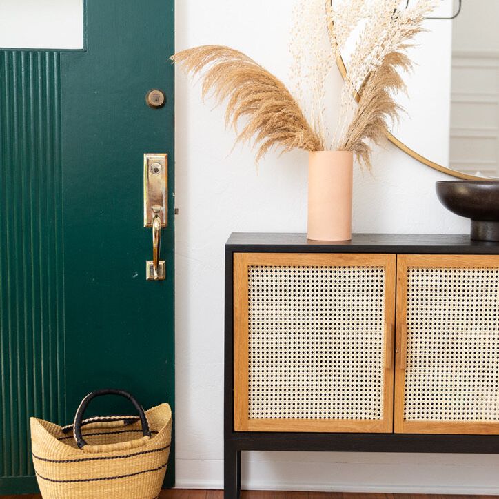 入口处有一张编织的控制台桌子，一面圆镜子和一扇翠绿色的门