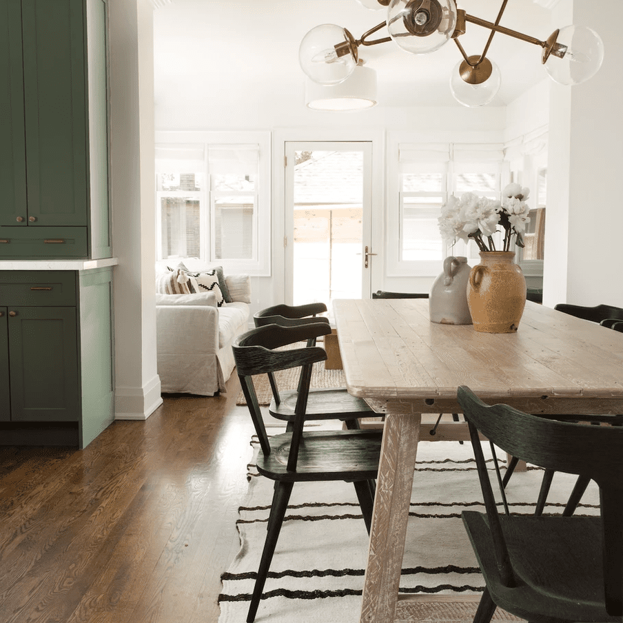 一张木制餐桌，上面有一个米色陶瓷花瓶和一个装满鲜花的橙色陶瓷花瓶