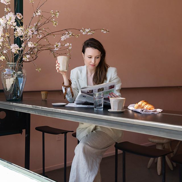 女人通过阅读报纸，而不是使用自己的智能手机回避社交媒体。