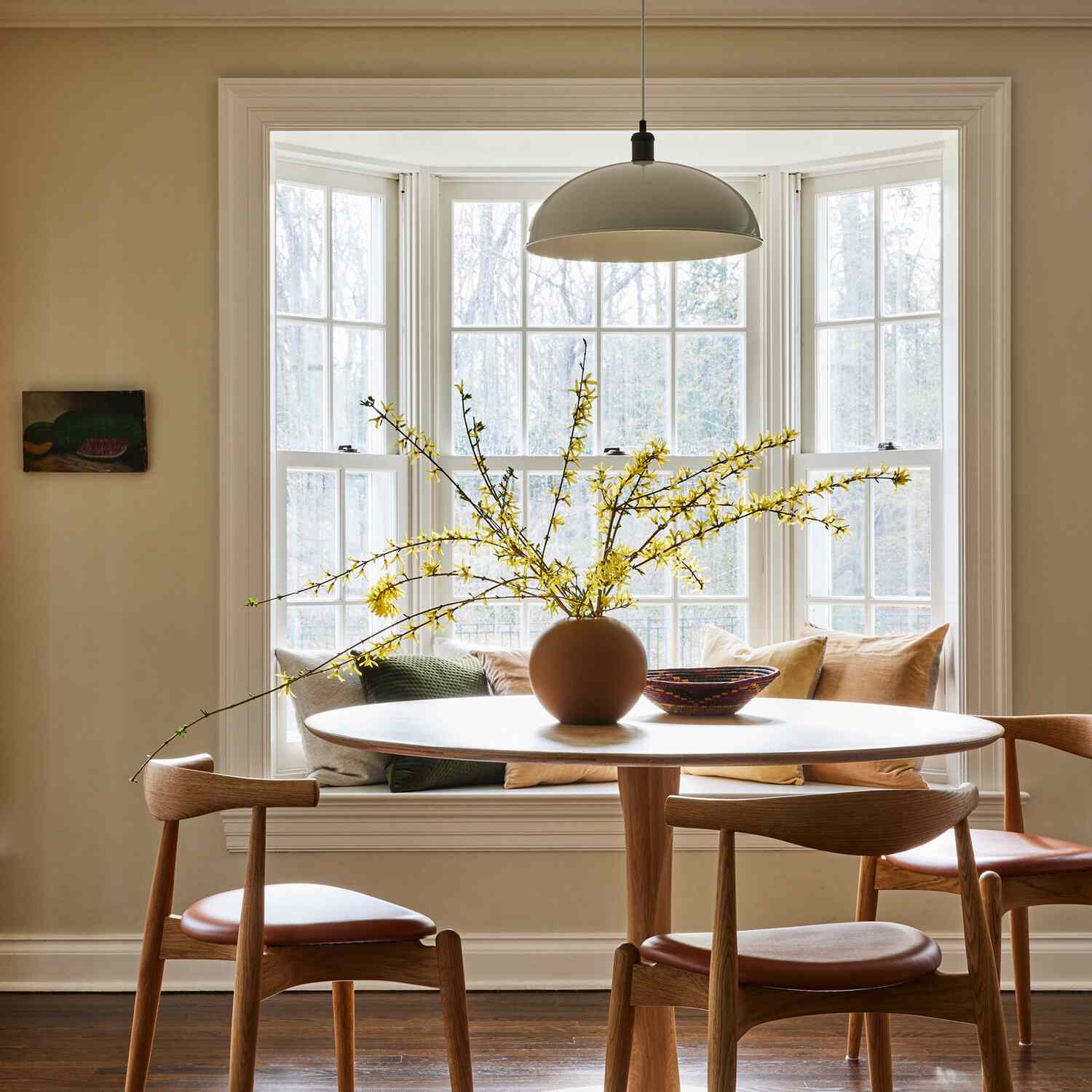 厨房的圆形桌子，上面有一个装饰用的小碗和一个装满了蔓生树枝的圆花瓶