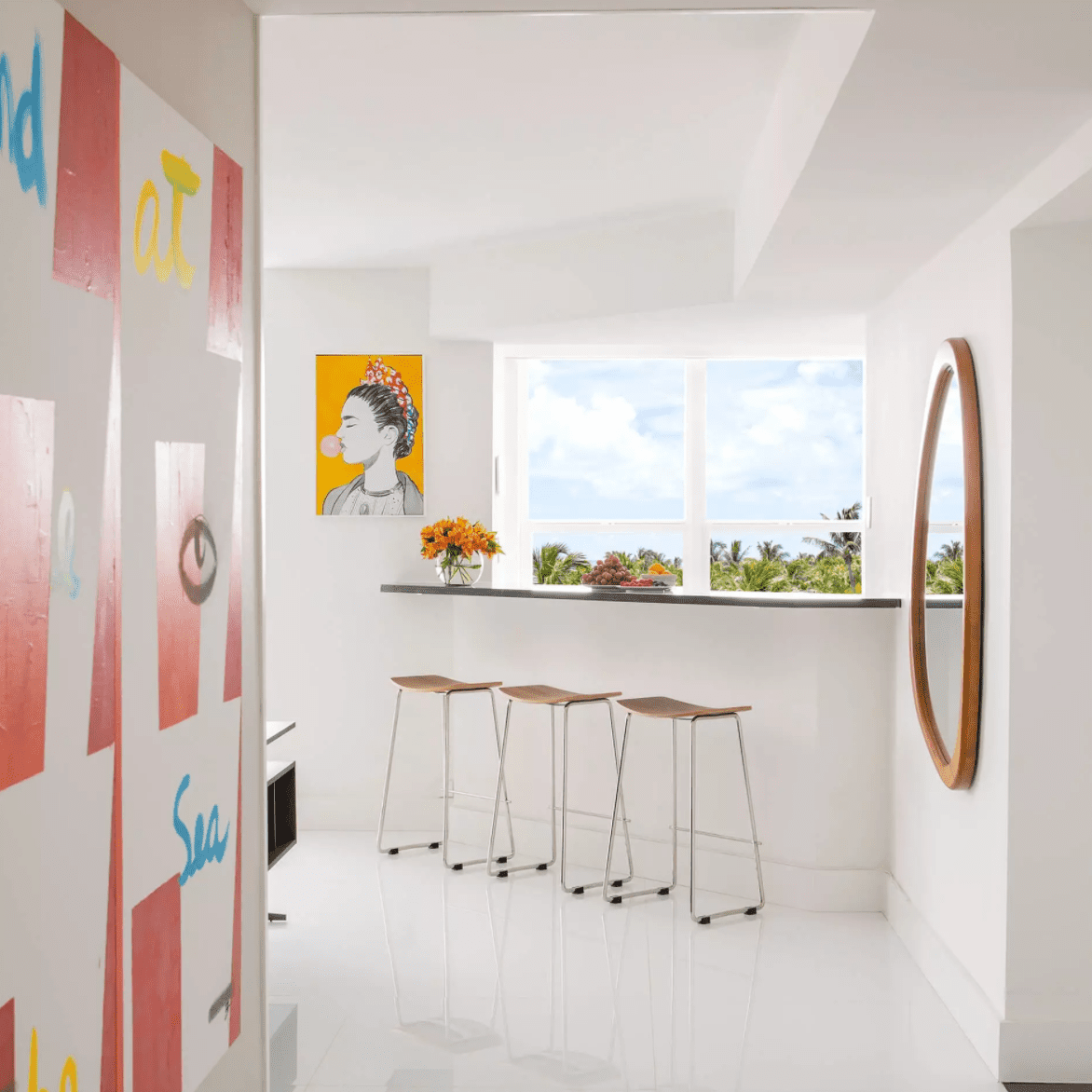 一条走廊通向一间全白的厨房，几面墙上摆放着现代艺术品