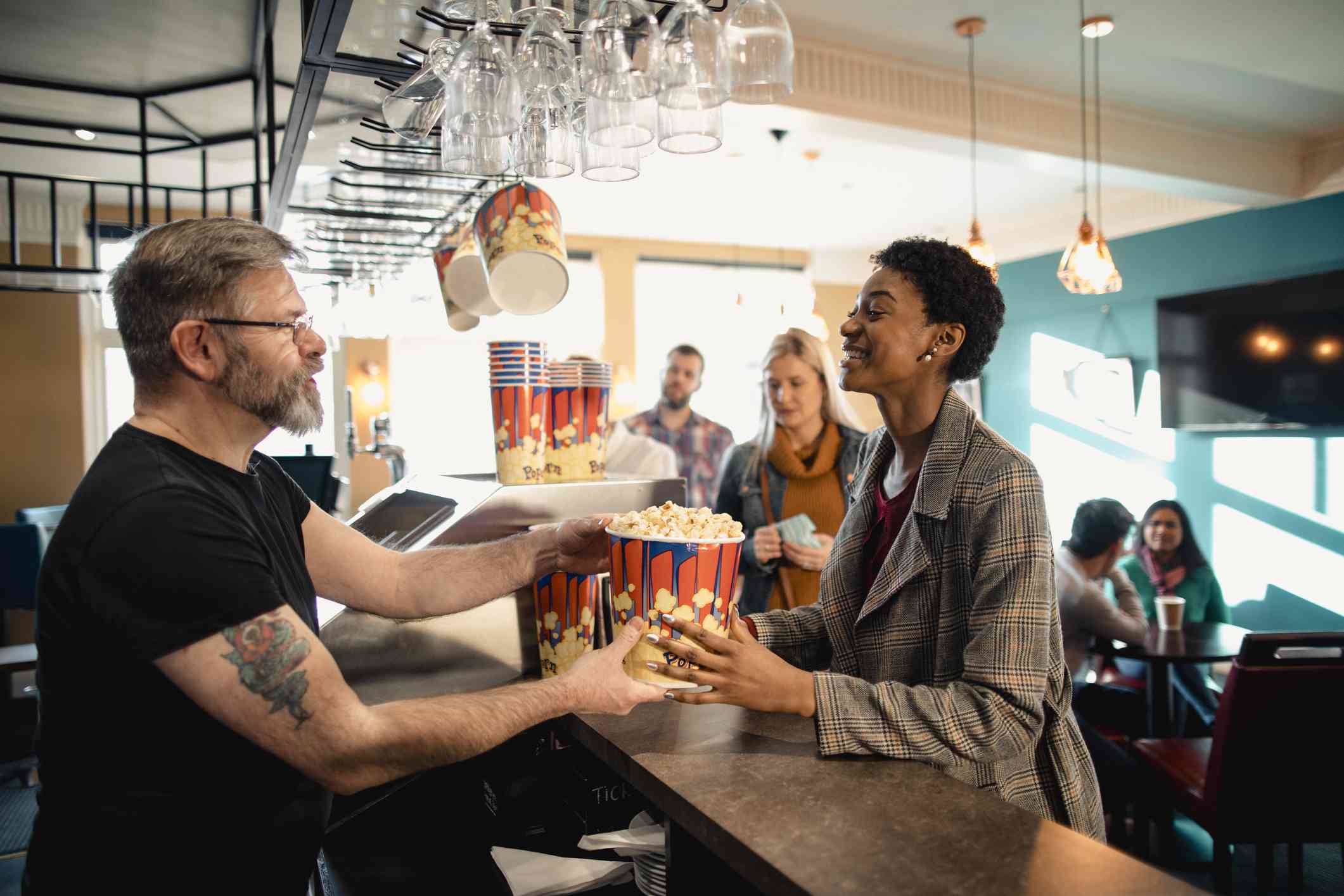 女人从影院员工获得爆米花。