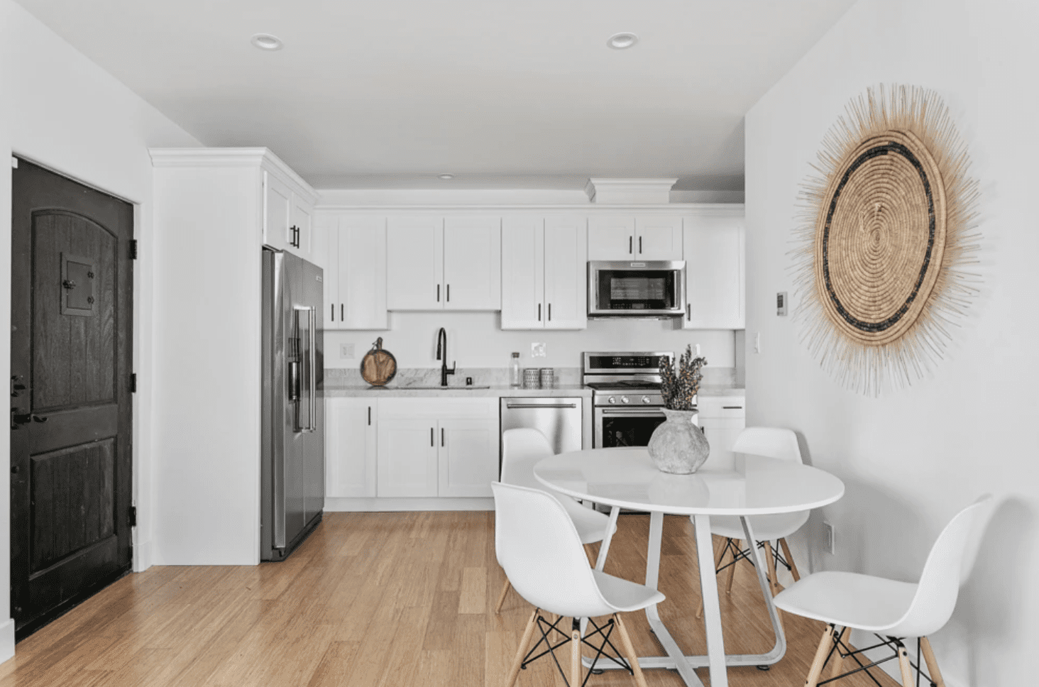 一个小的白色厨房，配有匹配的白色餐厅