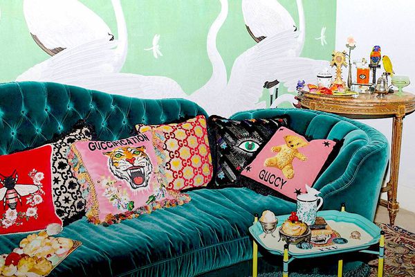 一个绿色的天鹅绒沙发，上面绣着Gucci靠垫。