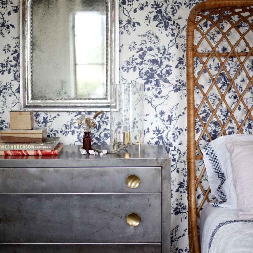 A bedroom with blue floral wallpaper on the walls