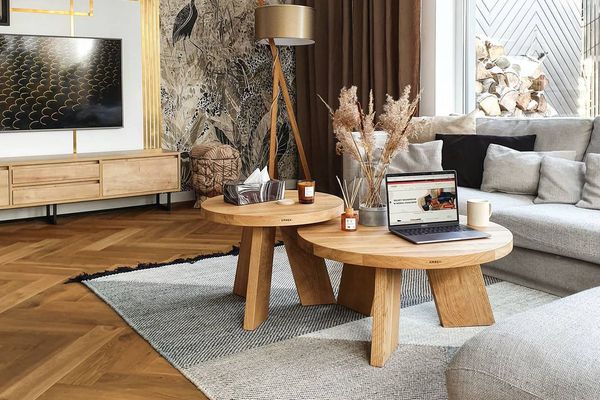 木制的咖啡桌放在灰色的地毯上，混合木媒体台和地板。