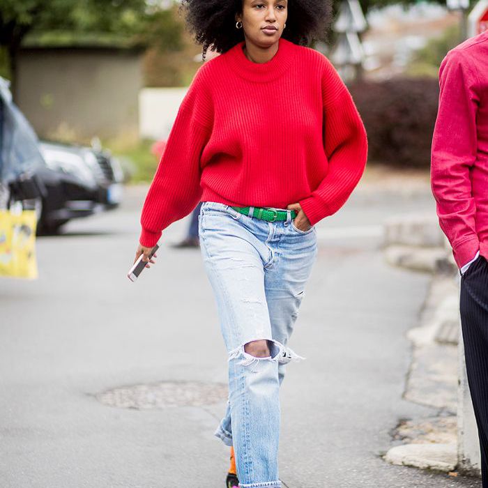穿着亮红色毛衣、宽松牛仔裤和短靴的女人