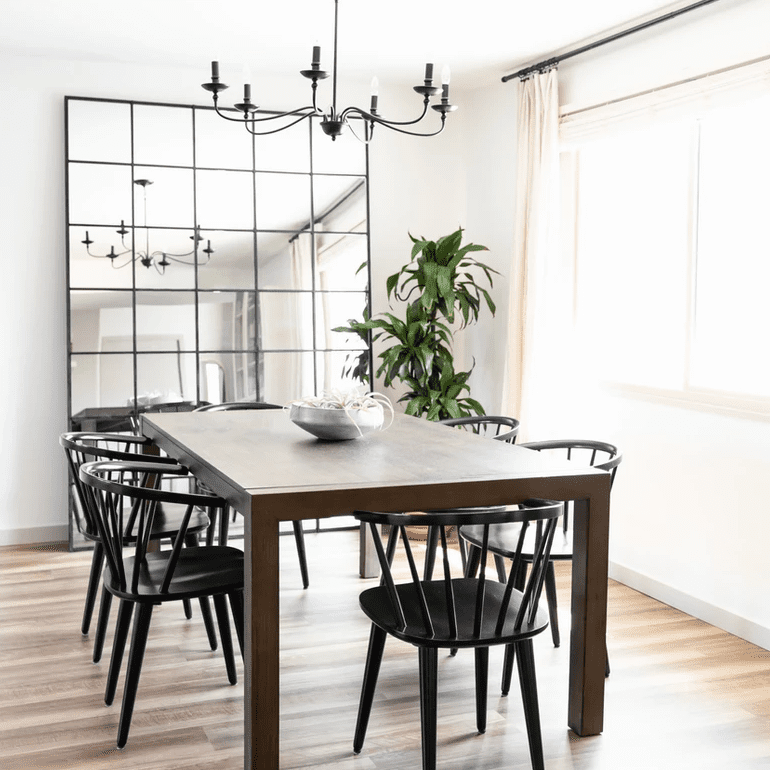 餐厅里有一盏黑色的枝形吊灯，配套的黑色镜子和黑色的椅子