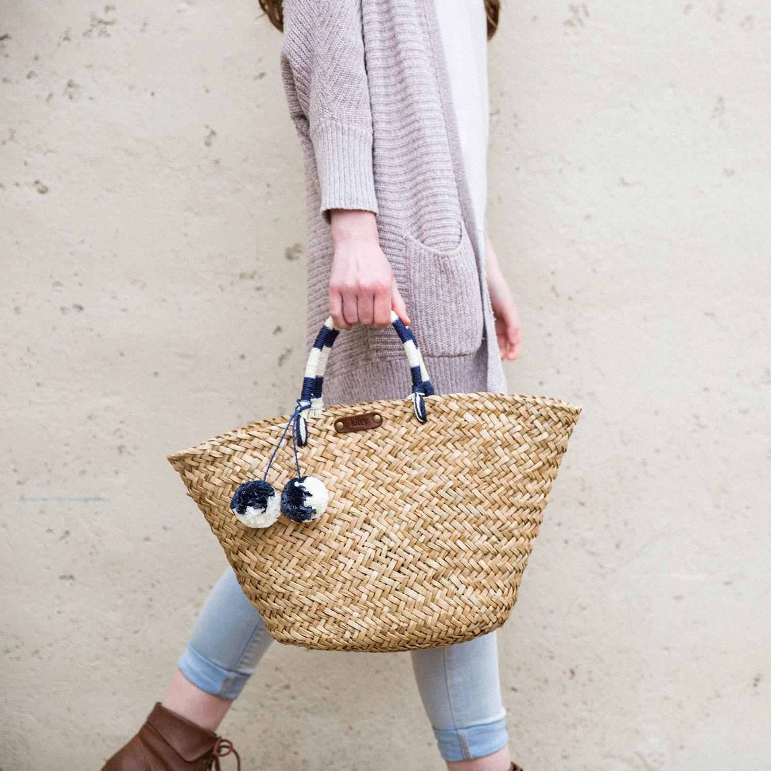 同时保持与蓝色和白色的条纹处理一个海草海滩袋女人走路。