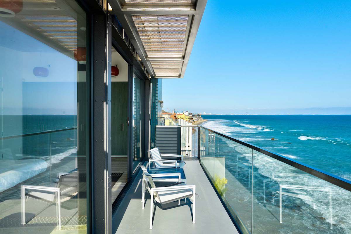 有一面玻璃墙的阳台，可以看到海边的景色