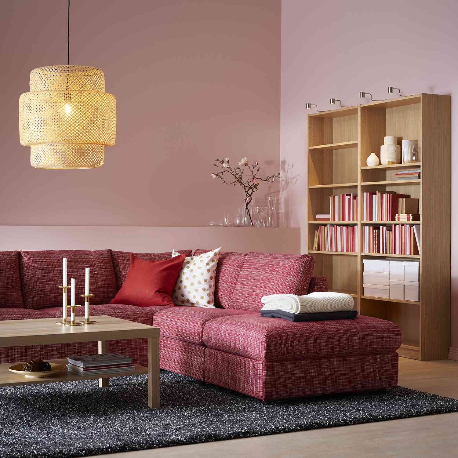 粉红色的客厅，红色的组合沙发和温暖的木质书架