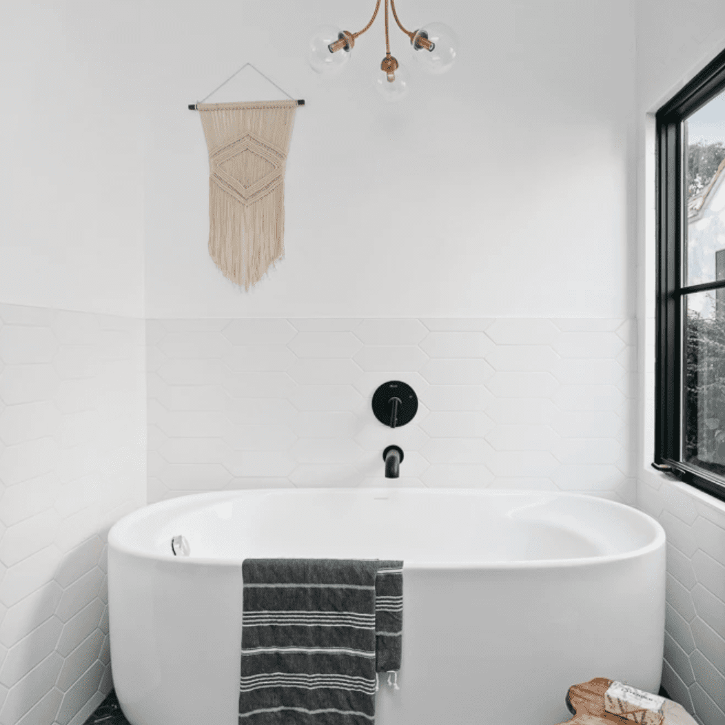 一间浴室里有现代化的照明设备，一个独立的浴缸，铺着黑色瓷砖的地板，还有几件装饰配件