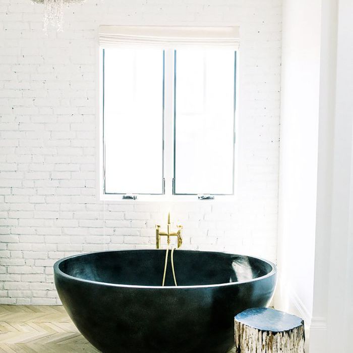 圆形浴缸和吊灯漆成白色砖浴室。