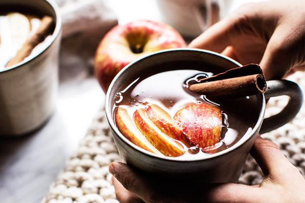拿着肉桂苹果饮料的人