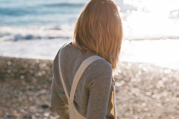 站立在海滩的妇女的后面