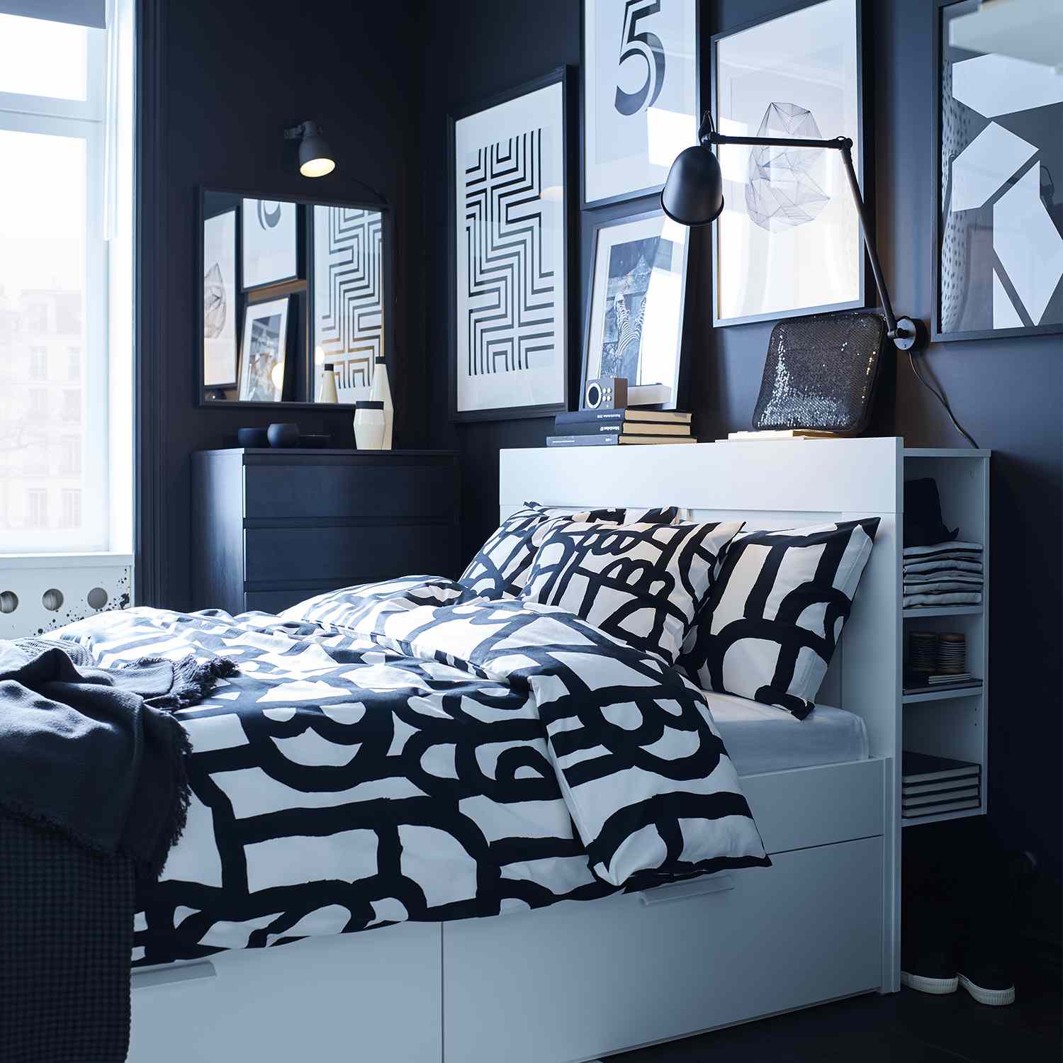 卧室有深色的墙壁，白色的床和黑白相间的床上用品。