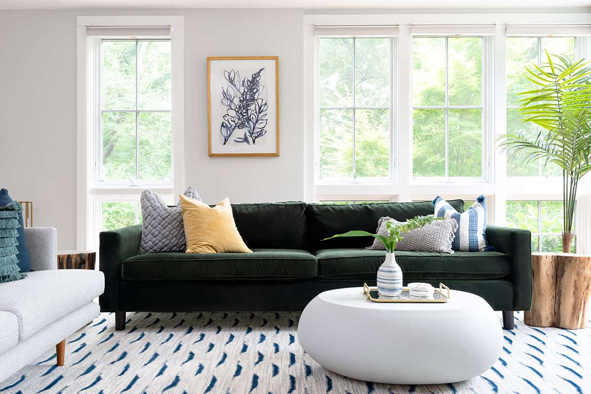 海滩房子客厅与棕榈和绿色沙发。