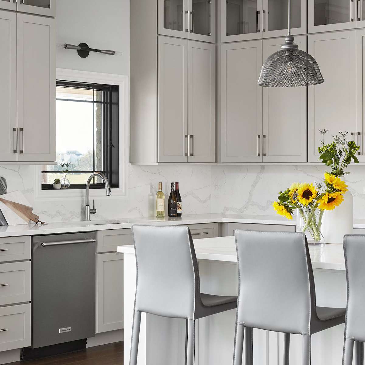 厨房有灰色厨柜，灰色的酒吧酒吧和银色电器