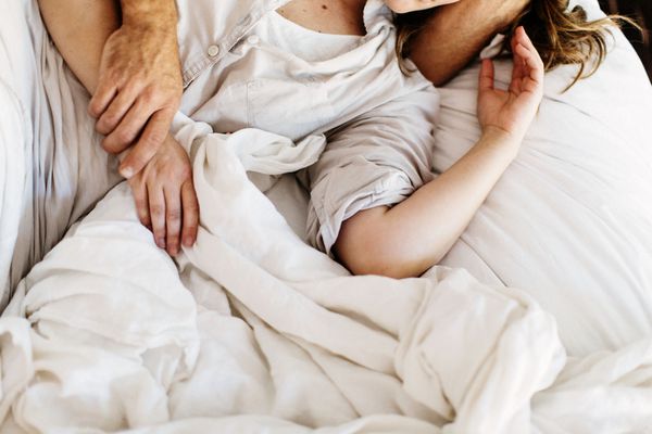 couple in bed under the covers arms around each other