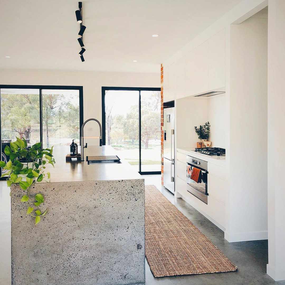 大混凝土岛在白色厨房里。