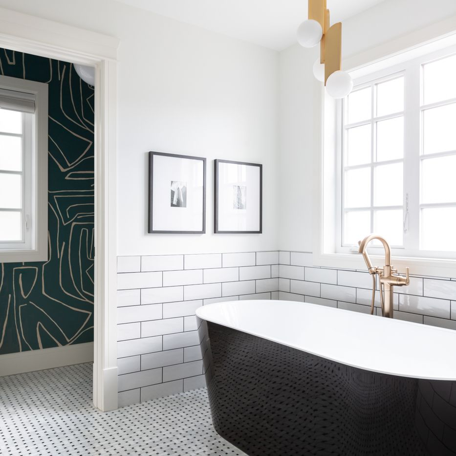一间装饰艺术风格的浴室，带有图案的领带地板，一个黑色的浴缸，和一个几何灯具