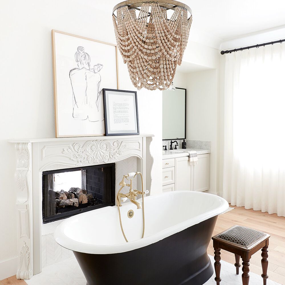 一个光滑的白色浴室，一个黑色的浴缸和一个串珠吊灯