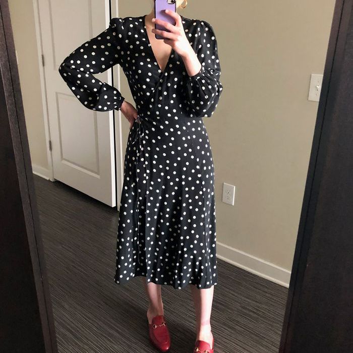 一个女人穿着黑白圆点连衣裙搭配红色的鞋。